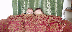 Two people hiding behind a sofa not talking to cult member
